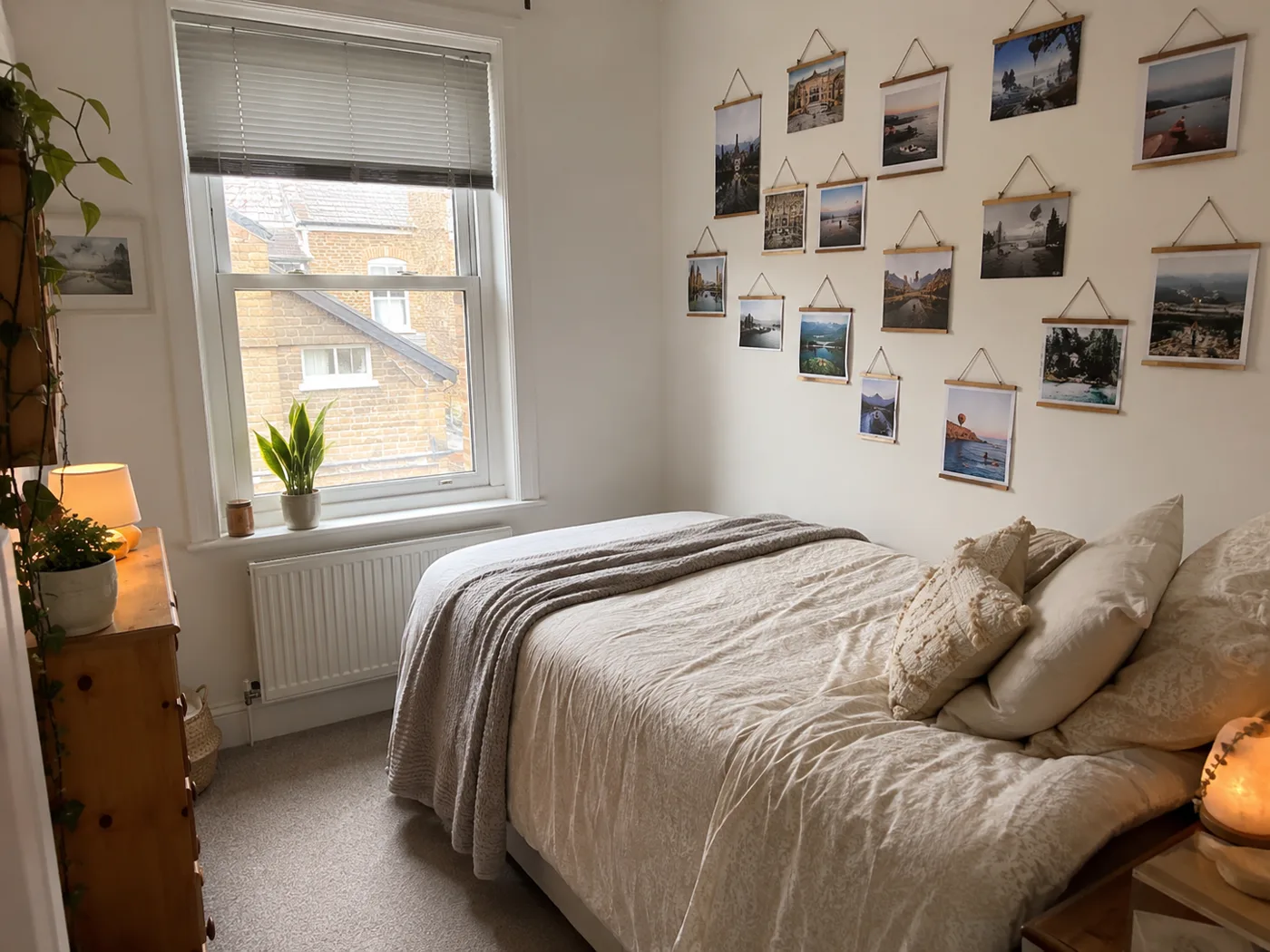 Gallery wall of photos beside bed in small bedroom