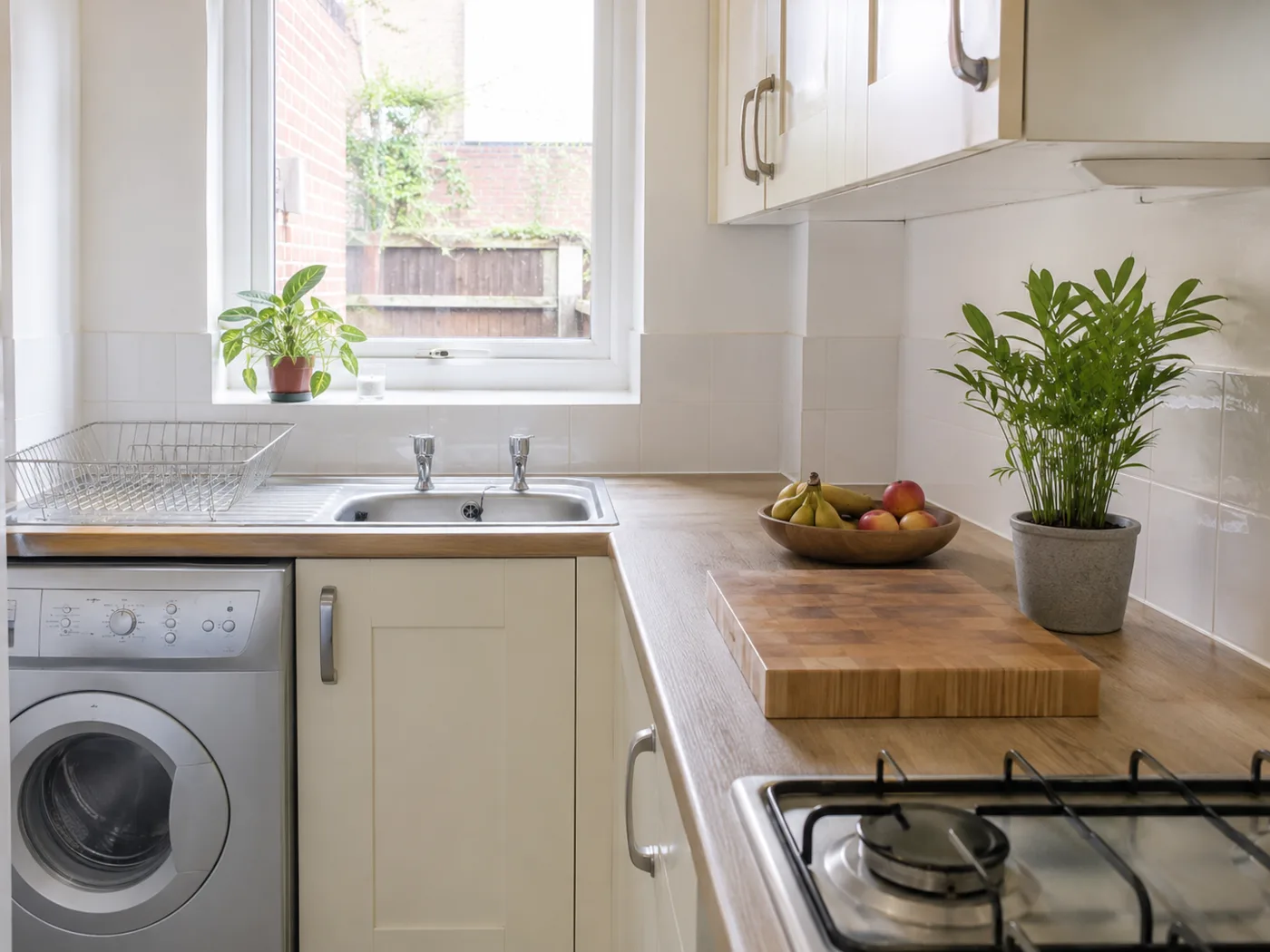 Clean kitchen counter with wooden chopping board fruit bowl and plant