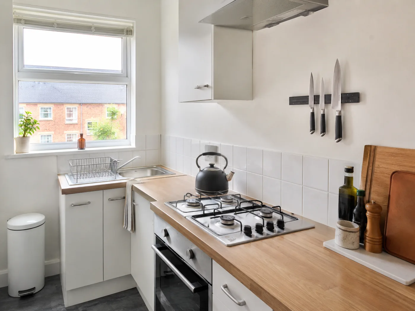 Kitchen with magnetic strip holding knives and cooking tools beside hob