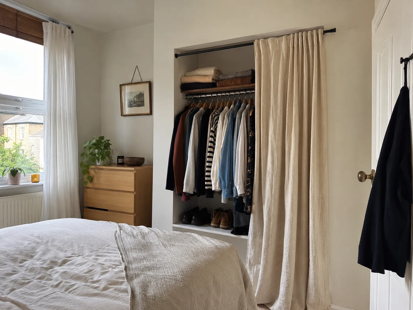 Tension rod with linen curtain used as wardrobe in bedroom alcove