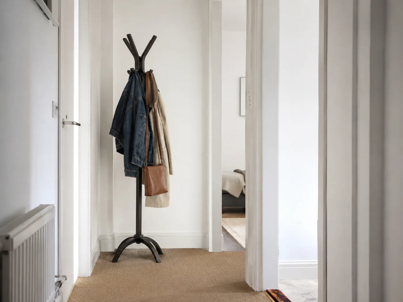 Freestanding coat rack with jackets and bags in hallway