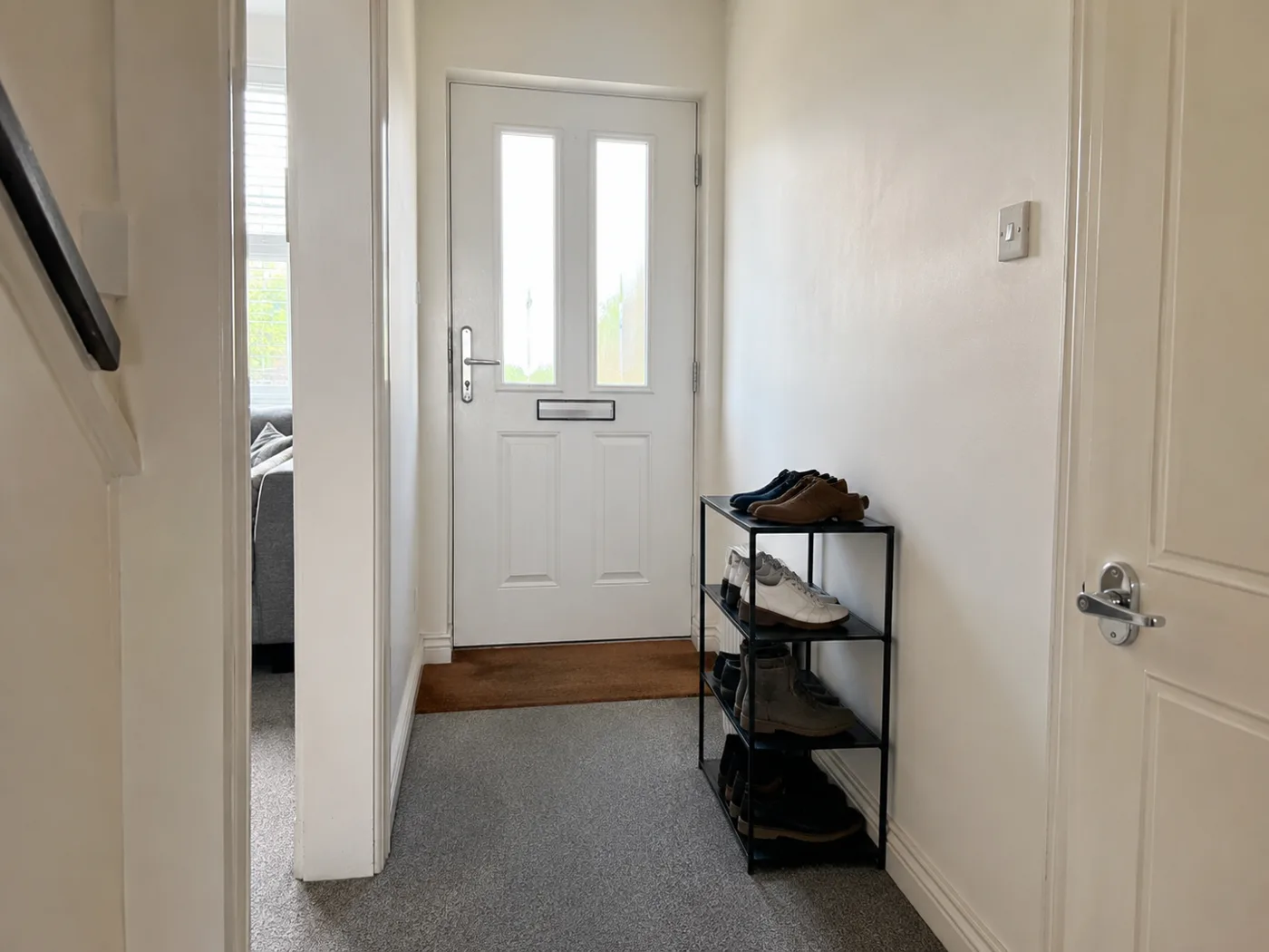 Freestanding shoe rack beside front door in hallway