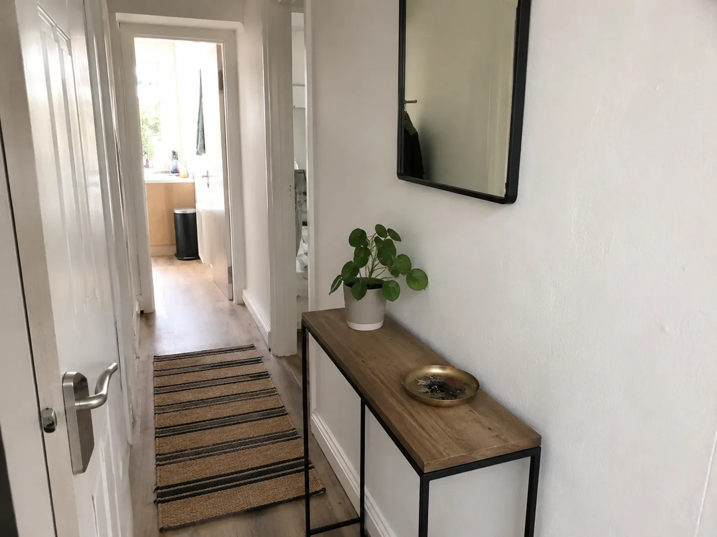 Narrow console table with mirror above in hallway