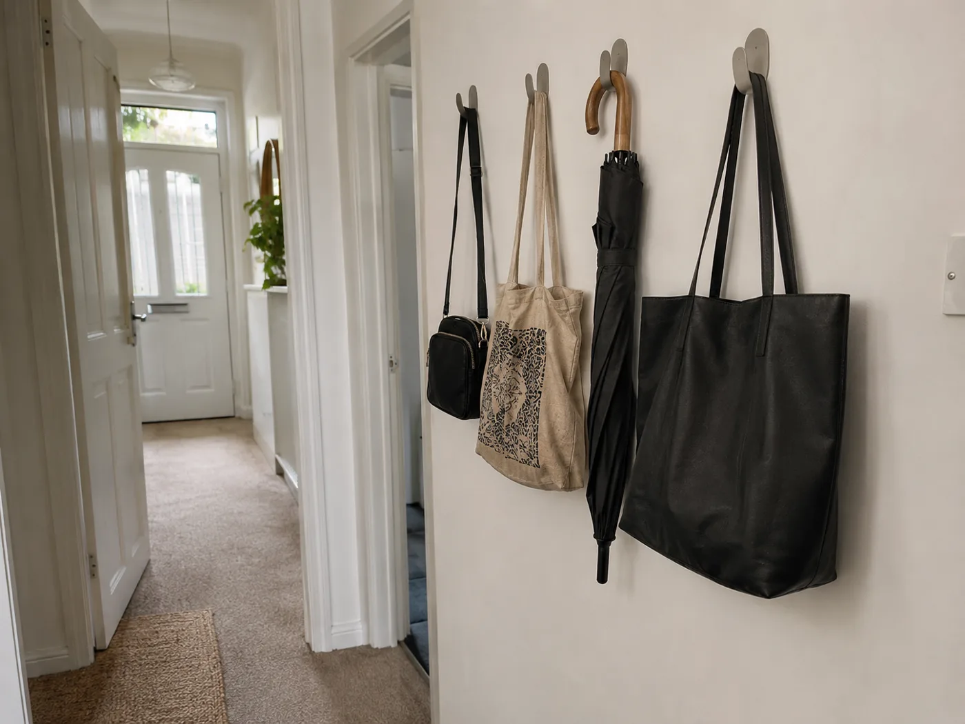 Hallway wall with adhesive hooks holding everyday bags and totes