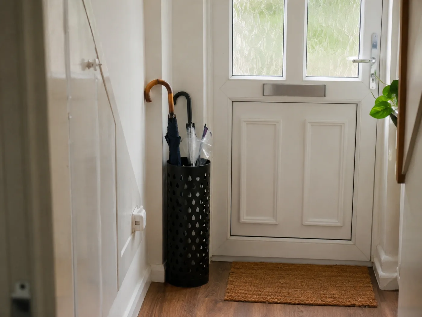 Freestanding umbrella stand beside front door in hallway