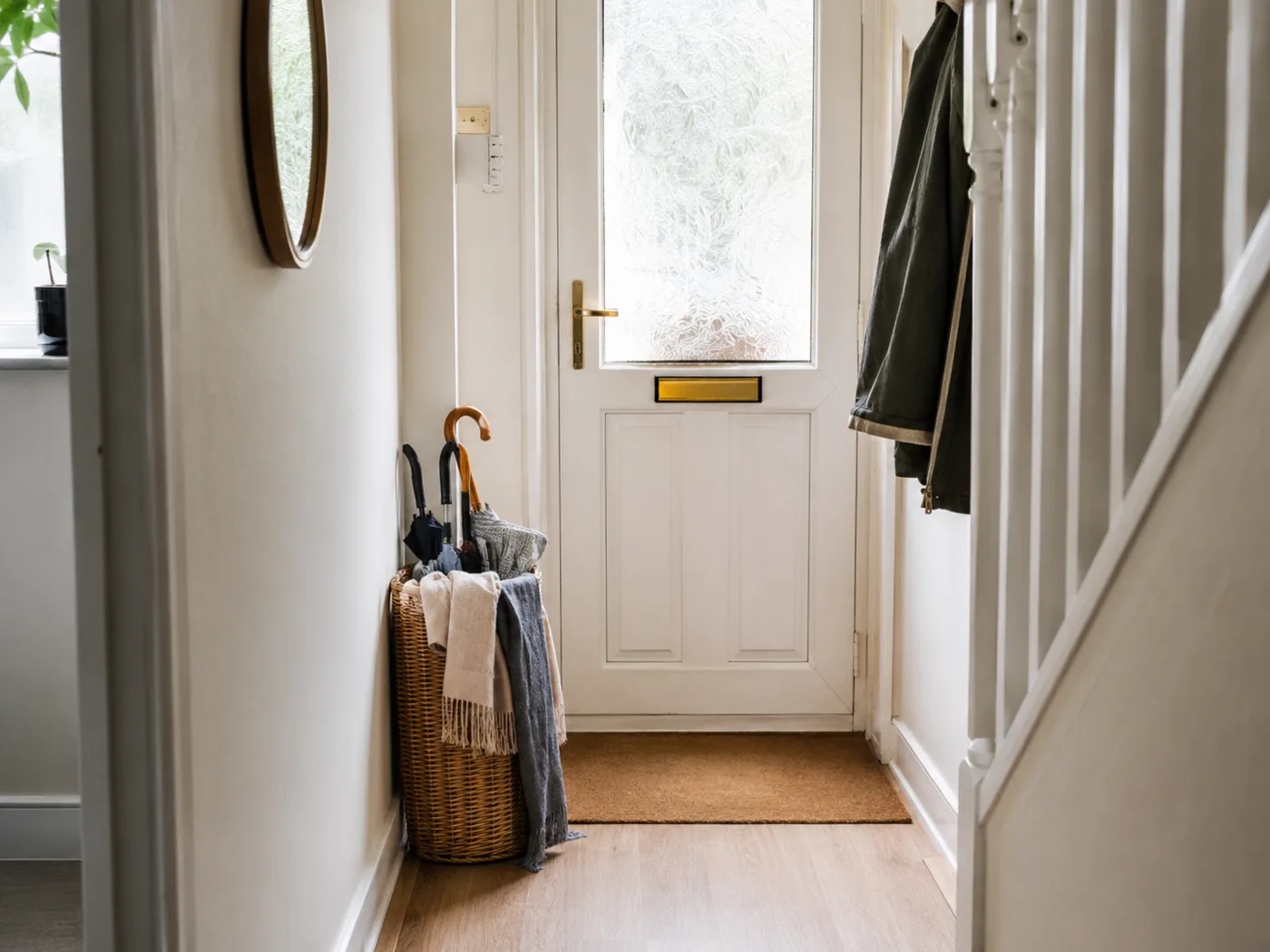 Wicker storage basket beside front door for umbrellas and scarves