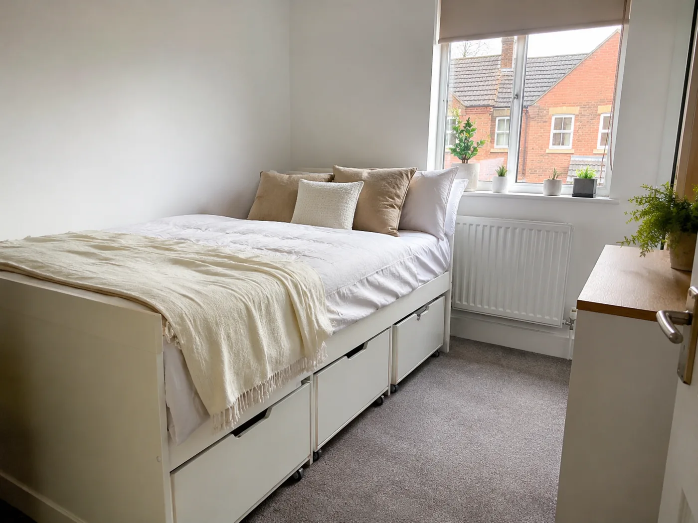 Under-bed storage drawers on wheels beside bed
